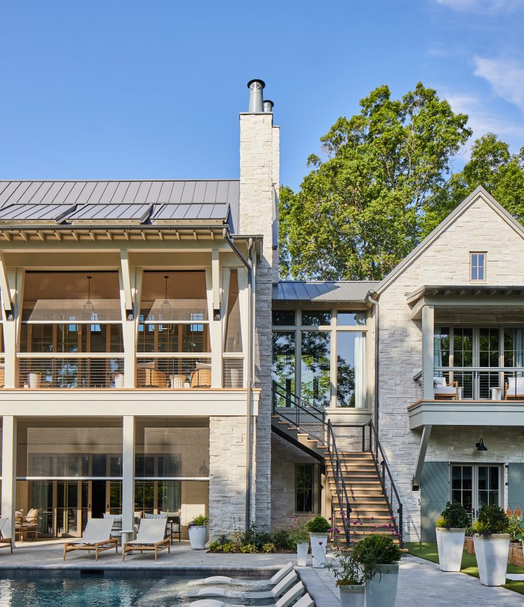 exterior of a large luxury stone home with large windows and motorized window screens